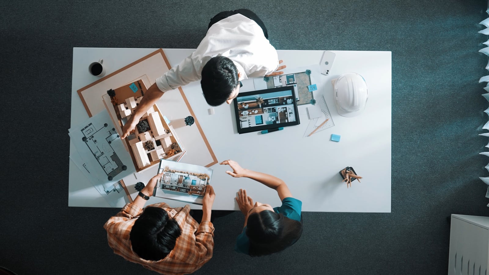 Overhead view of a work table: plans, models and samples shared by the project team.