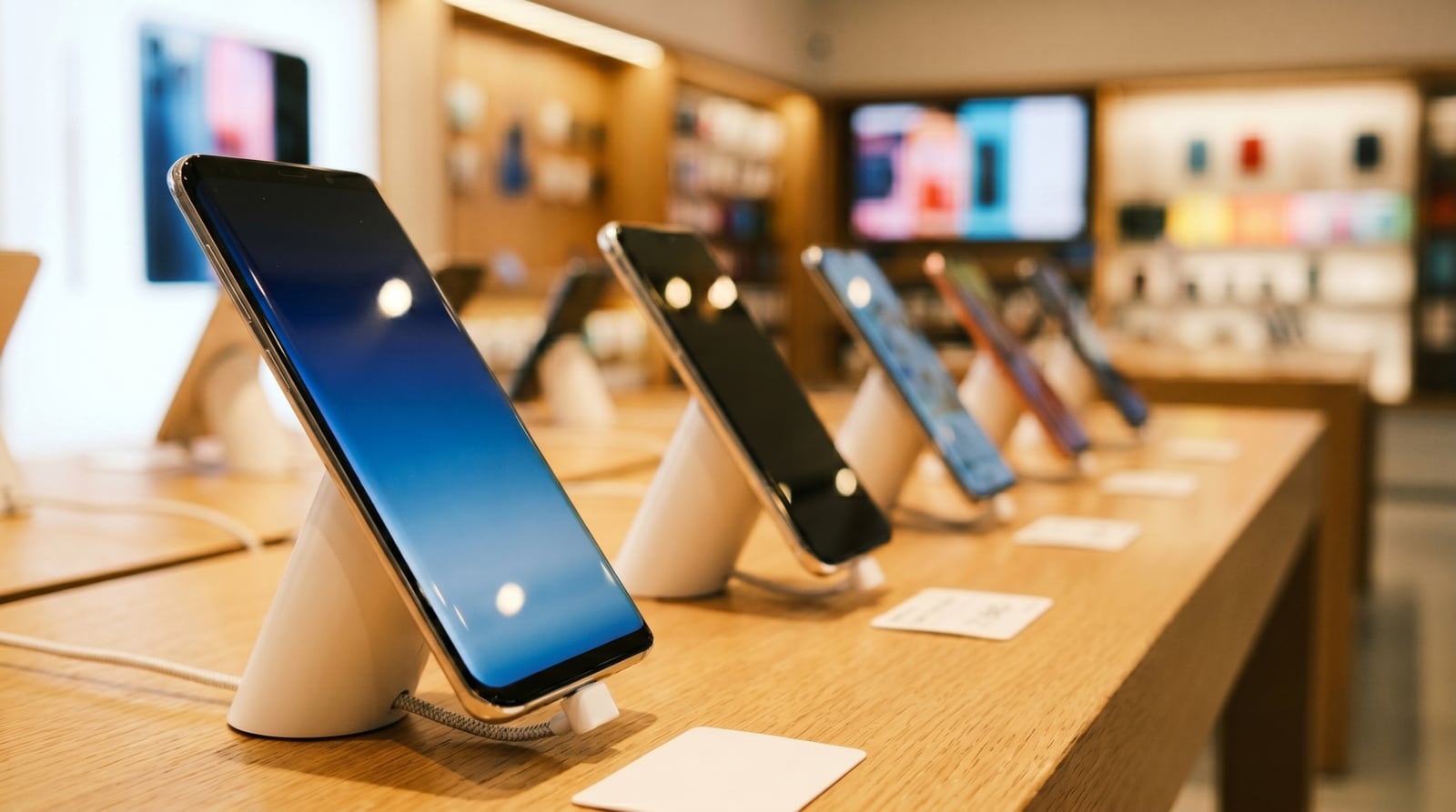 Phone display on a wooden table, in the middle of a shop floor.
